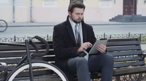 Businessman using a tablet sitting on a bench near the bicycle Stock-Footage 57113535