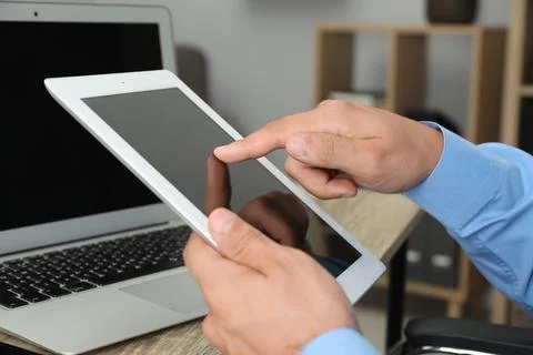 Businessman using tablet at table, closeup. Modern technology 库存照片