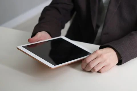 Businessman using tablet at white table indoors, closeup. Modern technology 스톡 사진
