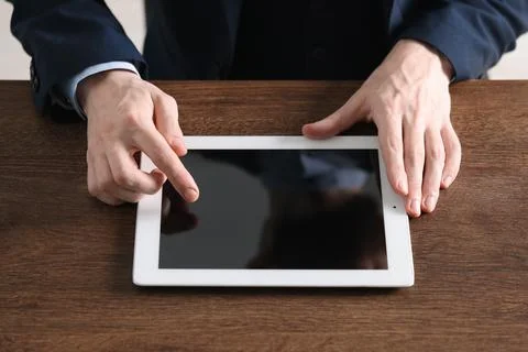 Businessman using tablet at wooden table, closeup. Modern technology 库存照片