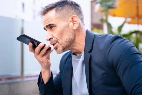 Businessman Using Voice Command on Smartphone Outdoors Stock-Fotos