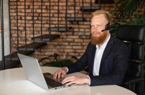Businessman using wireless headset and laptop computer Stock Photos