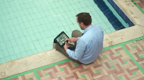 Businessman on vacations with tablet computer by the pool Stockbeeldmateriaal 10842080