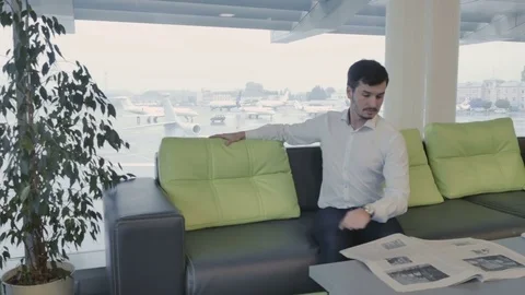 Businessman wait boarding on plane and reads newspaper in lounge hall Stock Footage