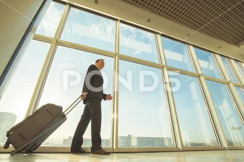 The businessman walk with a suitcase near panoramic windows Stock Photos