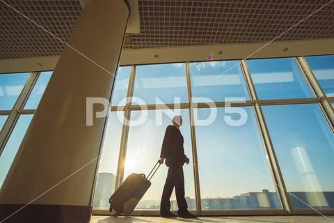 The businessman walk with a suitcase near panoramic windows Stock Photos