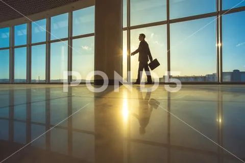 The businessman walk with a suitcase in the office hall Stock Photos