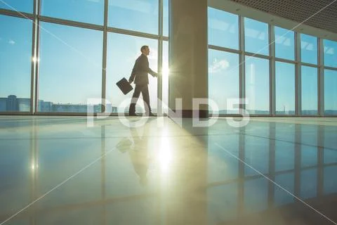 The businessman walk with a suitcase in the office hall Stock Photos
