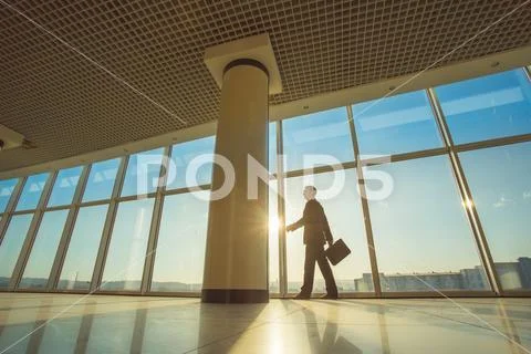 The businessman walk with a suitcase in the office hall Stock Photos