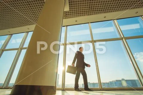 The businessman walk with a suitcase on the sunshine background Stock Photos