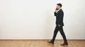 The businessman walking and phoning on the white wall background 4k or 4k+ Resolution