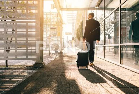 Businessman walking with bag outside airport Stock Photos