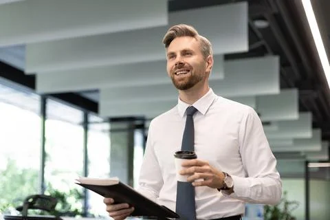 Businessman walking in office corridor with documents and takeaway coffee Stock Photos