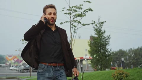 Businessman walking outdoors while talking on phone in urban area Stock Footage 285929923