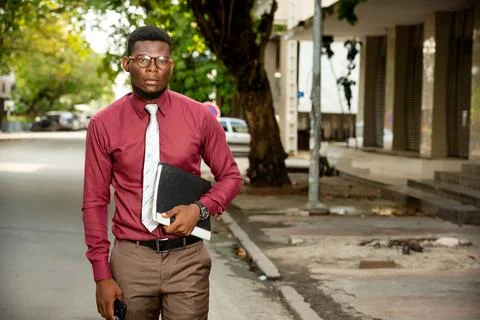 Businessman walking on the street holding a document in hand Photos