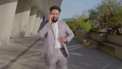 A businessman is walking through the city while confidently talking on his Stock Footage 305515056