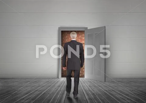 Businessman walking towards door open but blocked by red brick wall Stock Photos