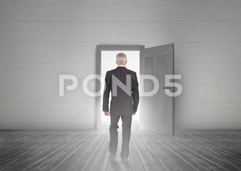 Businessman walking towards door showing light Stock Photos