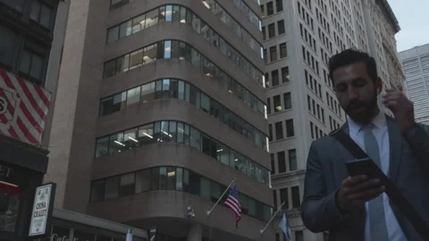 Businessman walking in urban environment using smartphone on busy street Stock Footage 312681256