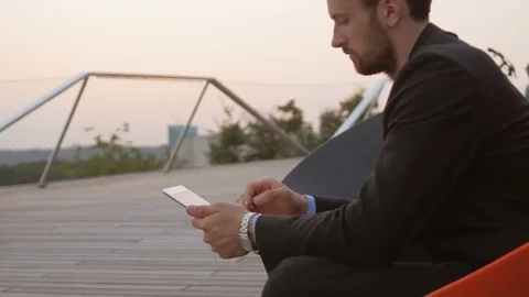 Businessman wearing a suit using a tablet outdoors. Stockbeeldmateriaal 76049257