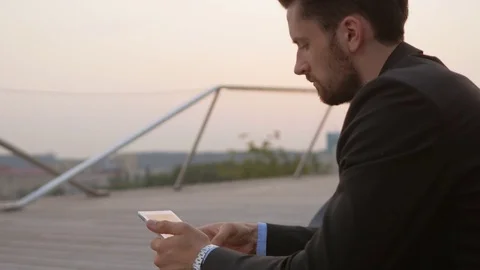 Businessman wearing a suit using a tablet outdoors. Stockbeeldmateriaal 76049296