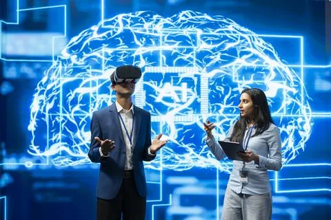 Businessman wears VR headset while businesswoman uses tablet to monitor AI Stock Photos