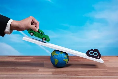Businessman weighs eco-friendly EV car on scale against CO2 symbol. Alter Stock Photos