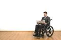 The businessman in the wheelchair holding papers on the white wall background Photo