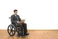 The businessman in a wheelchair sitting with a laptop on a white wall backgro Photo