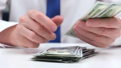 Businessman in white shirt counts stack of cash hundred-dollar bills of the USA. Stock Footage 197504496
