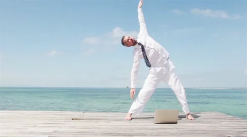 Businessman in white suit doing yoga on a wooden bridge with a laptop Stock Footage 59365284
