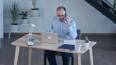 Businessman work on computer while talking on smart phone Vídeos de archivo 77417808