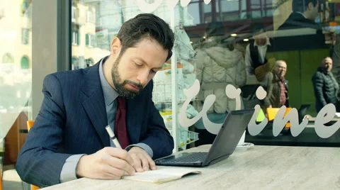 Businessman at work with laptop and notepad sitting at the table of a cafeteria Stockbeeldmateriaal 48749966