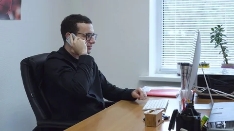 Businessman at work talking on cellphone by table in office. Stock Footage 76286228