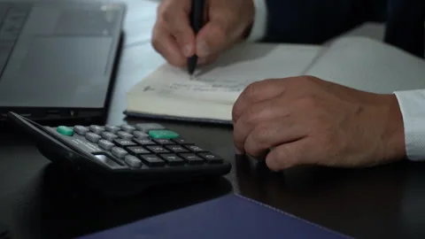 Businessman working with calculator taking notes in notebook Stock Footage 244744347