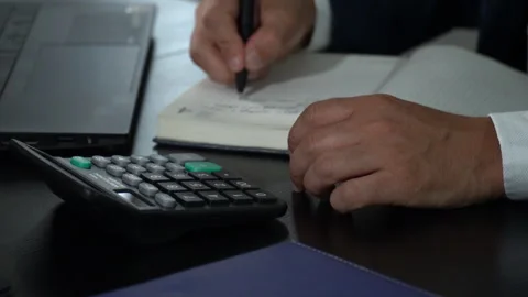 Businessman working with calculator taking notes in notebook Video stock 245084644