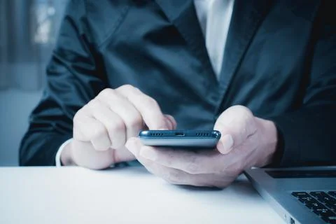 Businessman working on computer, man using smart phone and laptop in office. Stock Photos