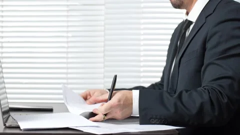 Businessman working at desk with document and using laptop, close-up Stock Footage 291027003