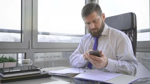 Businessman working with documentin ring binder, looking at camera, office 库存影片 73169857