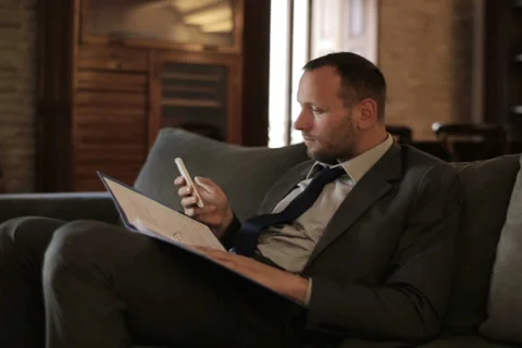 Businessman working with documents and smartphone sitting on the sofa NTSC Stock Footage 33139620