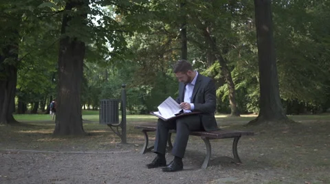 Businessman working with documents, sitting on bench in park. Vídeos de archivo 52723258