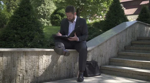 Businessman is working with documents, sitting on wall. 動画素材 52773062