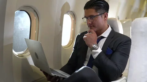 Businessman working on laptop computer sitting inside an airplane with sun li Stock Footage 147238731