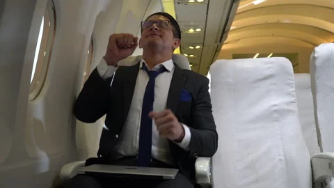Businessman working on laptop computer sitting inside an airplane yawning and Stock Footage 147240219