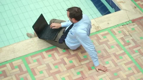 Businessman working on laptop by the pool Vídeos de archivo 10848787