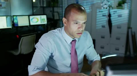 Businessman working late looks tired and uncomfortable as he loosens his tie Stock Footage