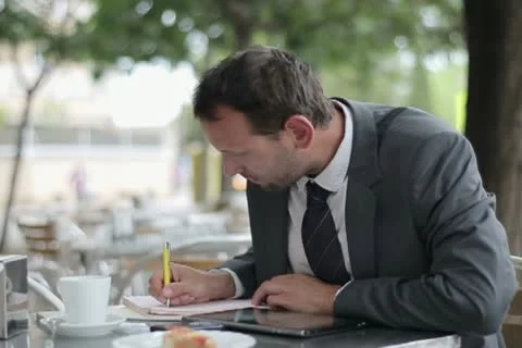 Businessman working with tablet and documents in outdoors cafe NTSC Stock Footage