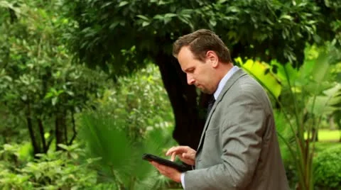 Businessman working on tablet computer in the park, steadicam shot Vídeos de archivo 10854195