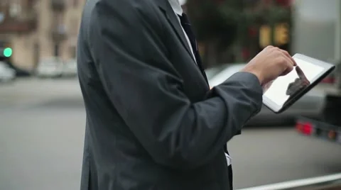 Businessman working on tablet computer by the street, steadicam shot HD Stock Footage 11098991