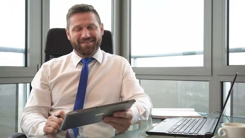 Businessman working on tablet, smiling at camera, in office, portrait,close shot 库存影片 72362022